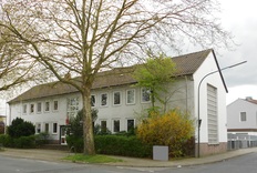 Seitenansicht des zweistöckigem weißverputzten Gebäudes der Betriebsstelle des Mess- und Eichwesen Niedersachsen in Osnabrück, davor ein Baum