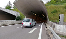 Peiseler Rad hängt an silberfarbenen VW-Bus, der gerde in einen Tunnel einfährt