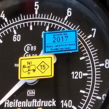 Eine blaue und eine gelbe Eichmarke kleben auf der Analoganzeige eines Reifenluftdruckprüfers mit einem Messbereich bis 10 bar