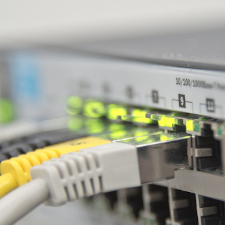Grau, weiße und gelbe Anschlusskabel an einem Netzwerkverteiler (Switch)