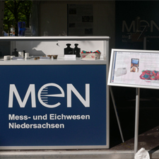 blaue Vitrine mit MEN Aufschrift auf denen sich Gewichte befinden, daneben ein Aufsteller