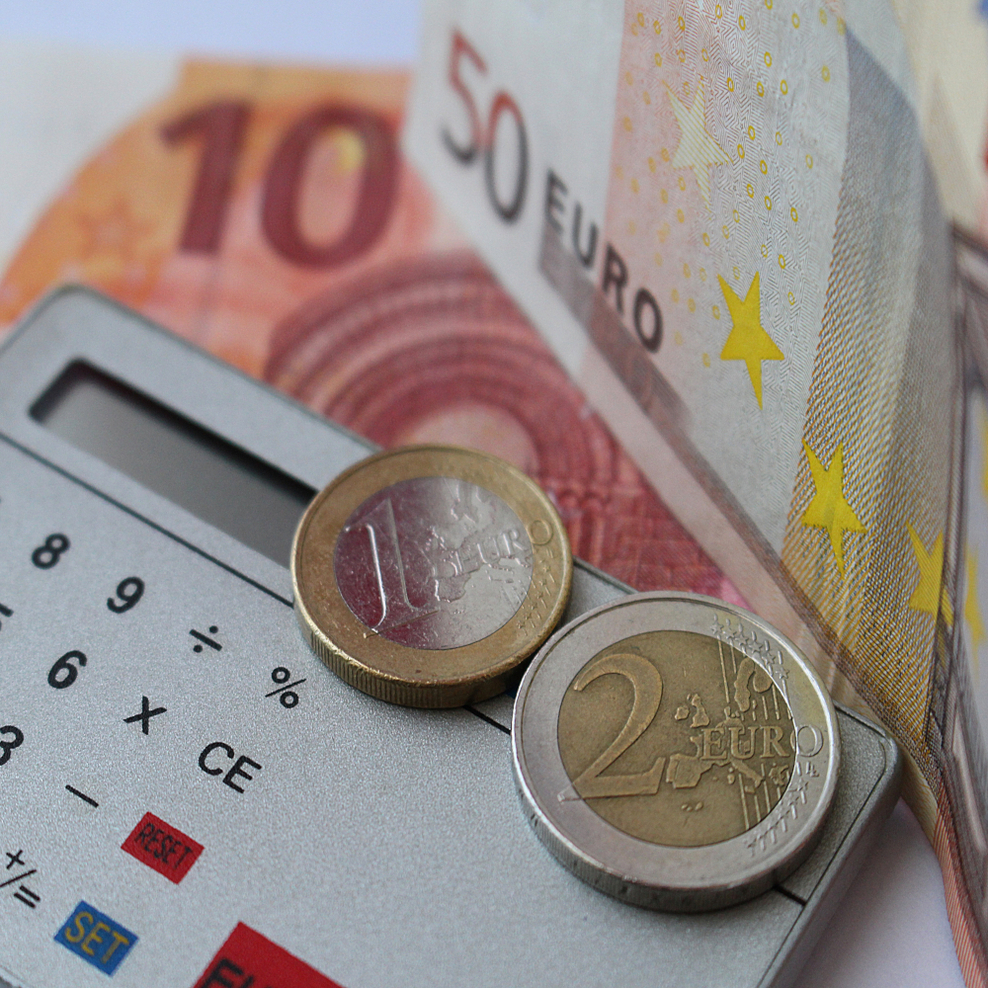 zwei Euromünzen und 2 Gelscheine mit einem Taschenrechner