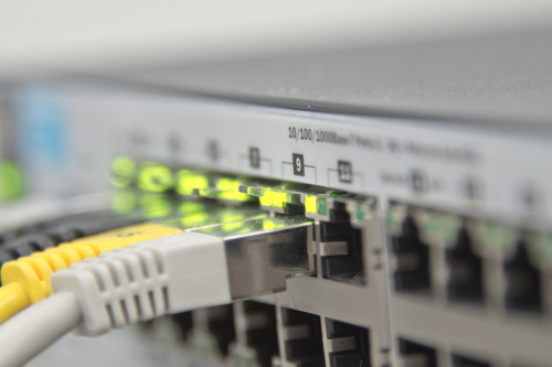 Grau, weiße und gelbe Anschlusskabel an einem Netzwerkverteiler (Switch)