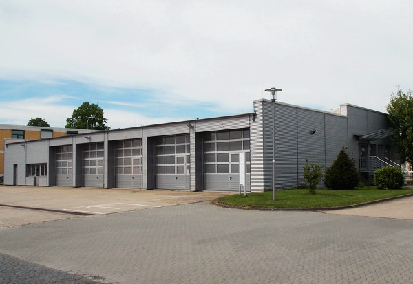 Seitenansicht des einstöckigen grauen Gebäudes der Betriebsstelle des Mess- und Eichwesen Niedersachsen in Braunschweig mit fünf Rolltoren und Flachdach