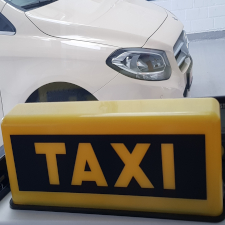 Ein Taxischild mit dem vorderen Teil einer Taxe im Hintergrund